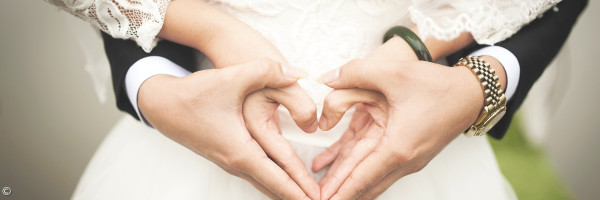 Hochzeitspaar, das mit den Händen ein Herz formt